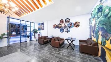 A modern lobby with a glass door entrance, a seating area with sofas and a coffee table, and a wall with hexagonal art pieces.