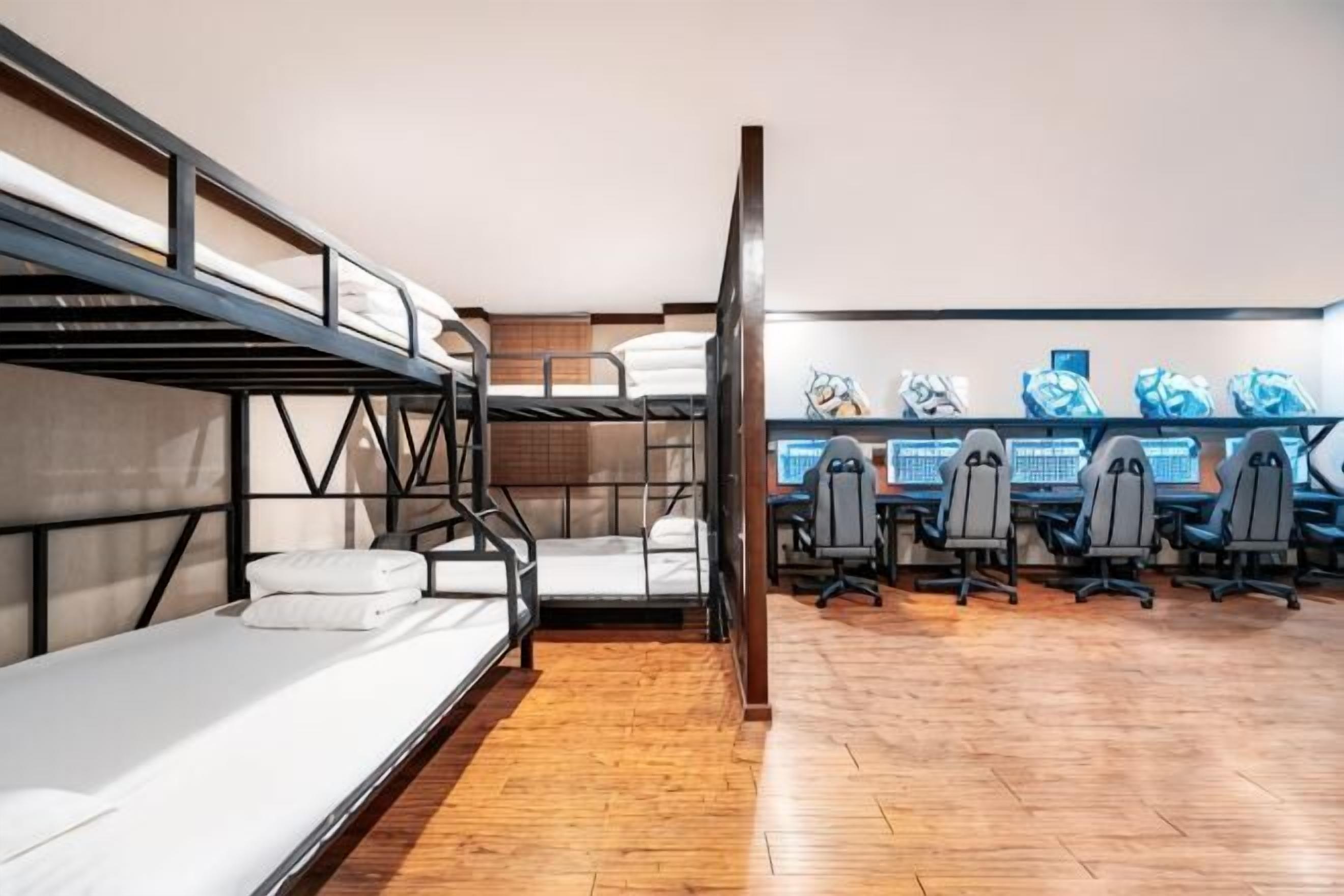 Een slaapkamer met stapelbed, bureau en meerdere stoelen.