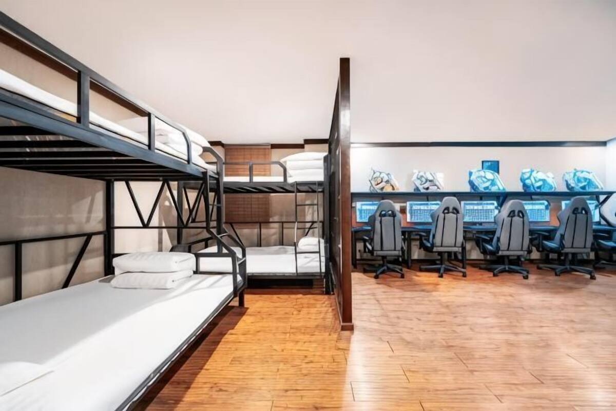 A bunk bed room with a desk area and multiple chairs.