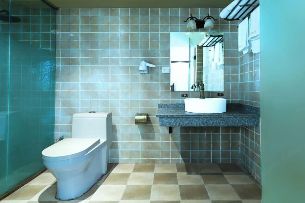 A bathroom with a toilet, a sink, and a shower area.