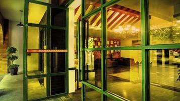 A hotel lobby with a large glass door, a chandelier, and a staircase.