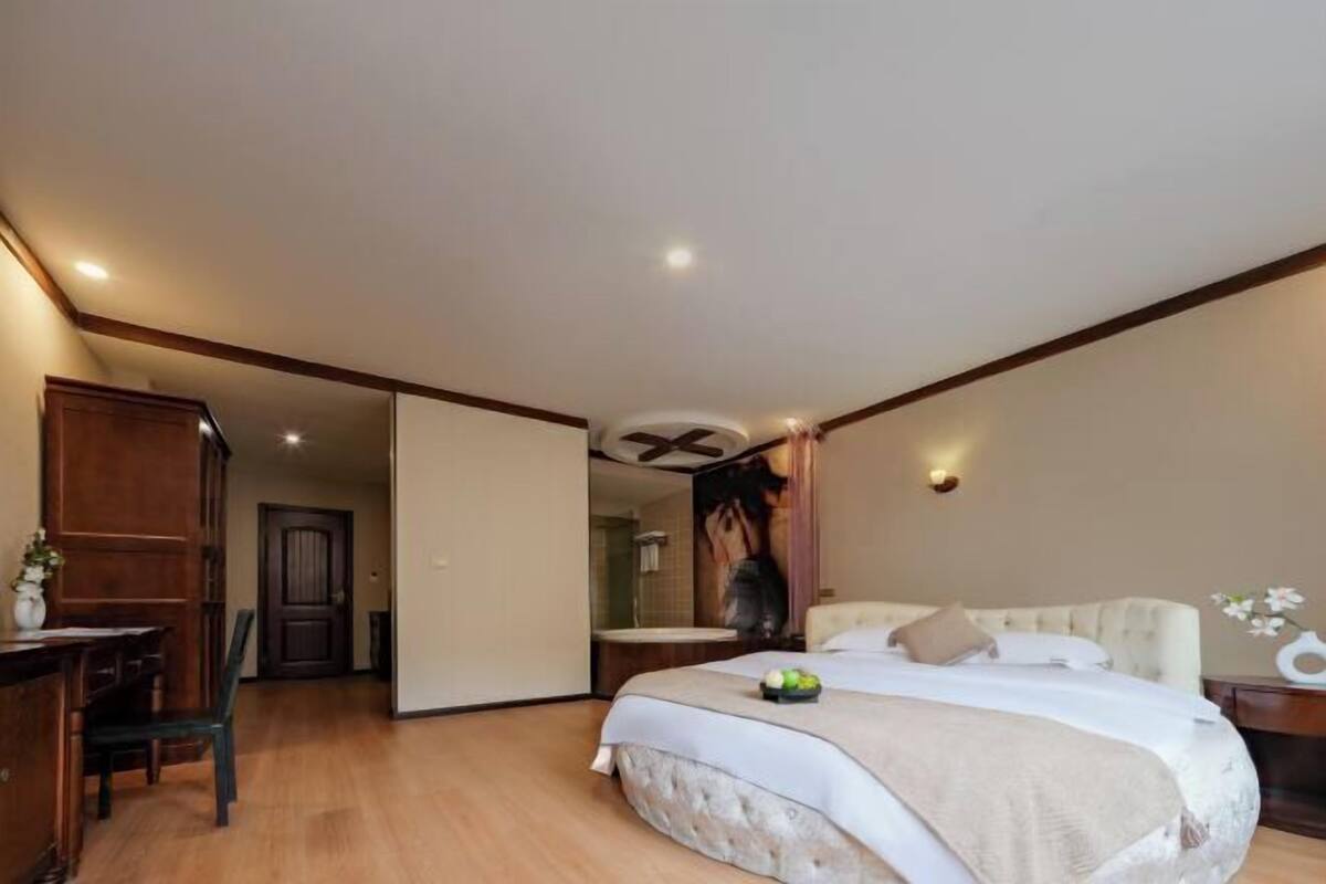 A bedroom with a bed, a desk, and a bathroom visible through an open door.
