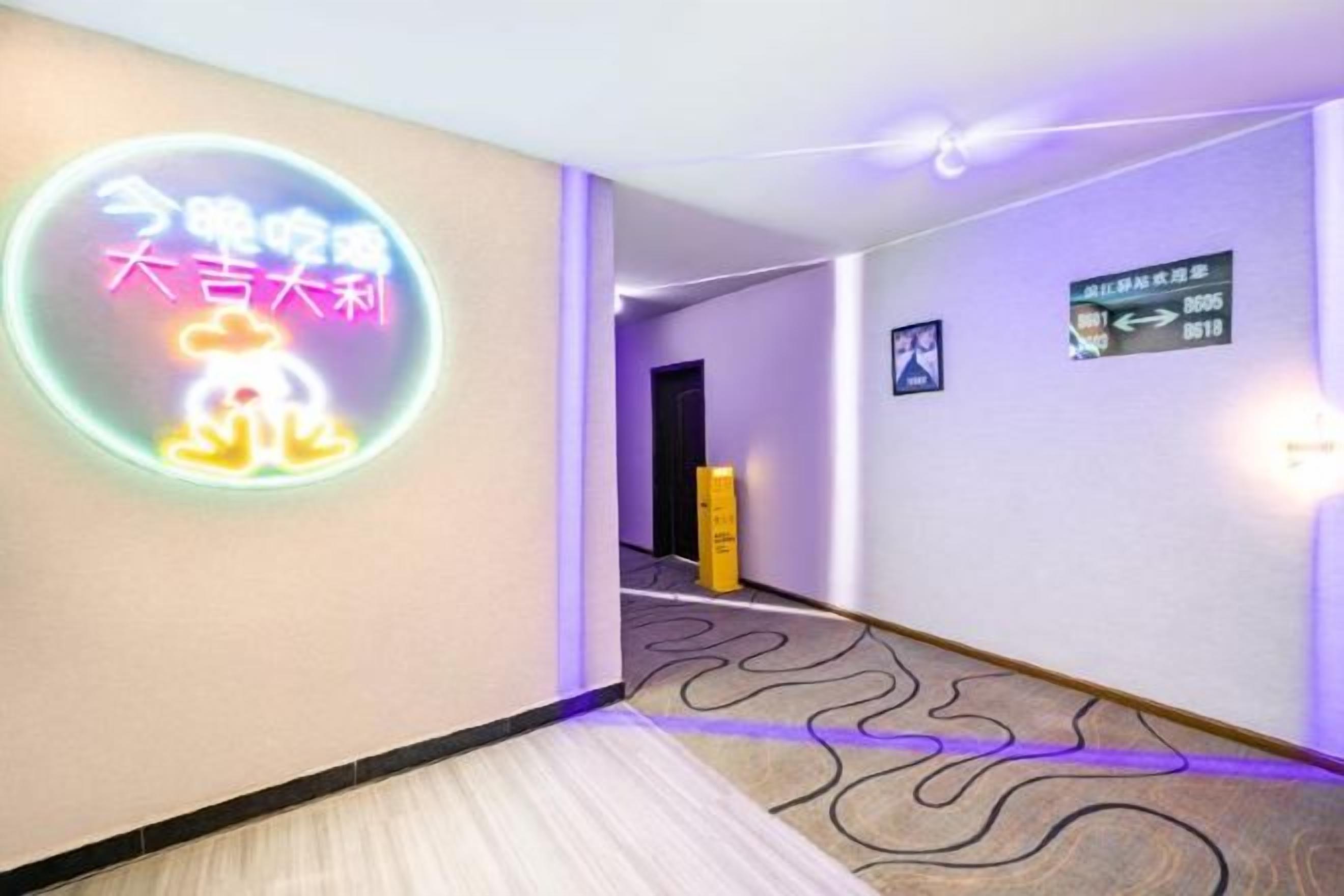 Un corridoio d'albergo con un neon, indicazioni direzionali e un tappeto decorato.