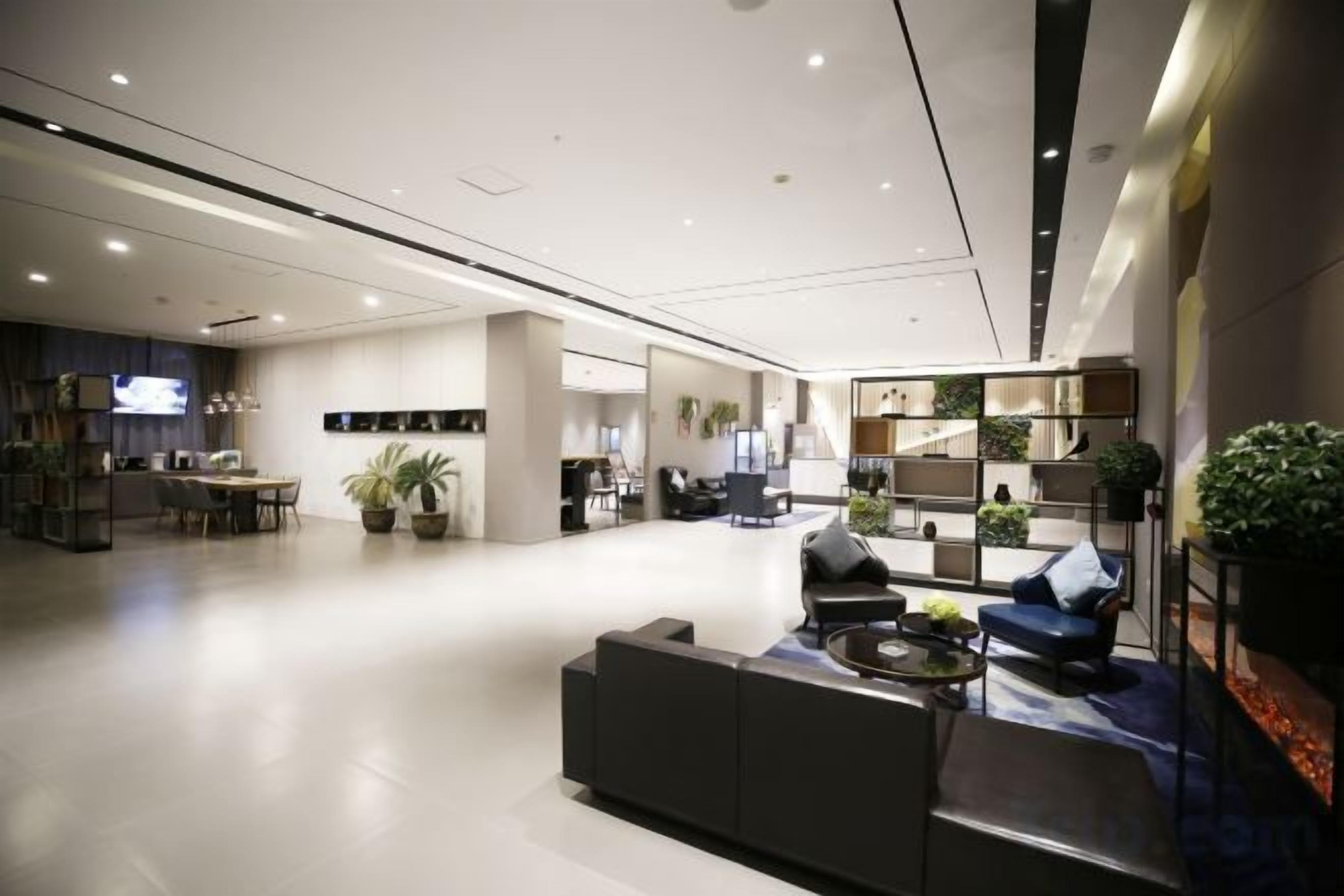 A spacious hotel lobby with a reception desk, seating area, and a kitchen in the background.
