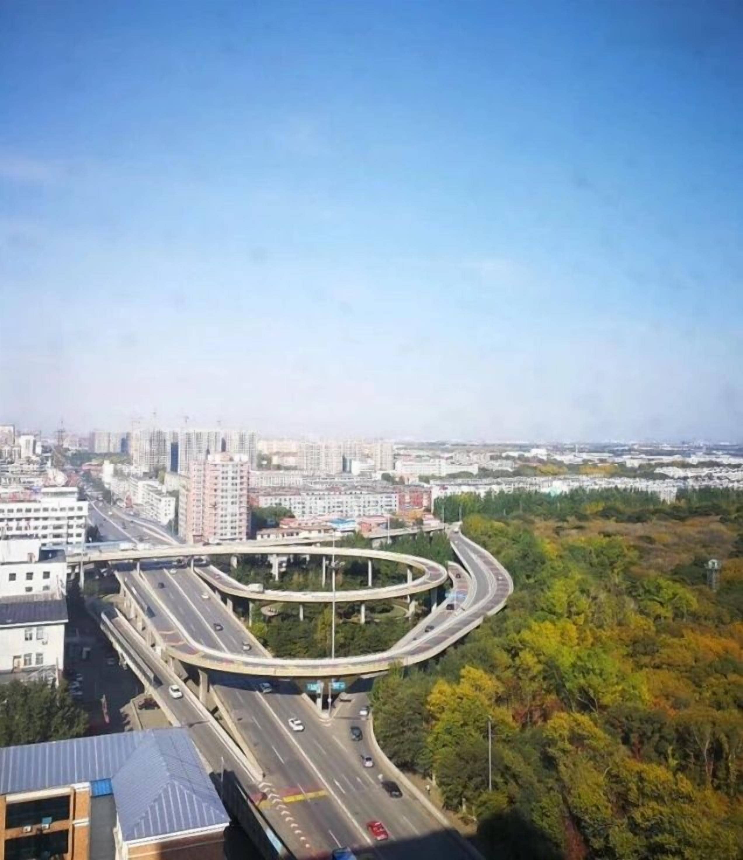 Un échangeur autoroutier à plusieurs niveaux, entouré de bâtiments urbains et de verdure.