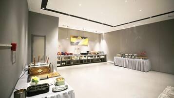 Amplia sala con una mesa de buffet, un mostrador de recepción y una zona de estar.