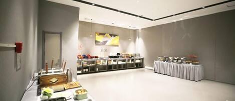A spacious room with a buffet table, a reception desk, and a seating area.
