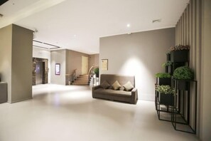A spacious living area with a sofa, a staircase, and a wall-mounted plant shelf. - Ease Hotel (Shenyang Changjiang North Street Beiling Park Branch) (Shenyang)