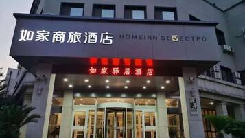 Entrada de hotel com porta giratória e placa indicando 'Homeinn Selected'.