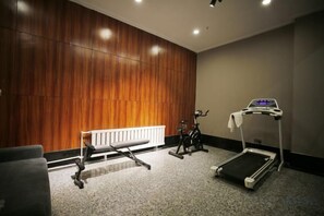 Une salle de sport équipée d’un tapis de course, d’un vélo d’exercice et d’un banc de musculation.