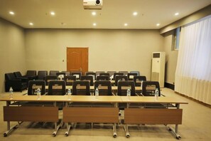 Une salle de conférence avec une longue table, des chaises et un projecteur.