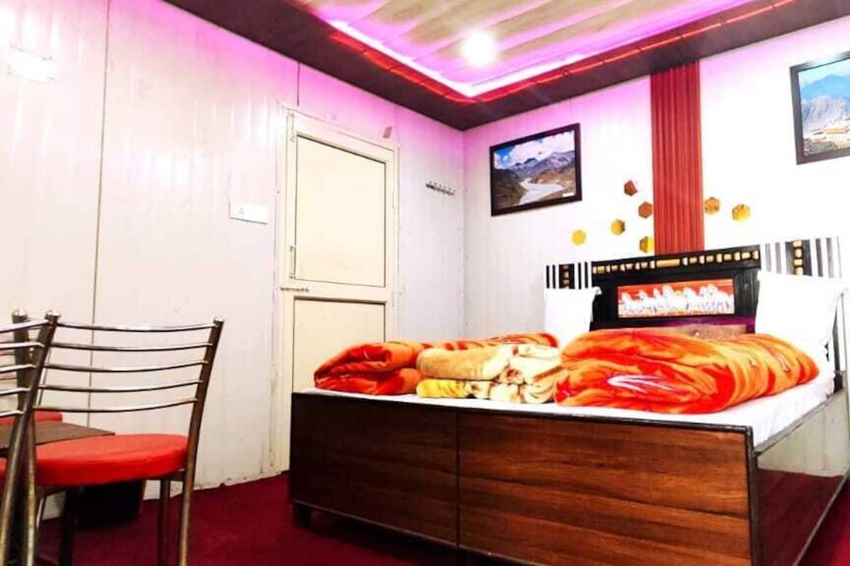 Un dormitorio con cama de madera, un escritorio y una silla. Hay dos cuadros en la pared.
