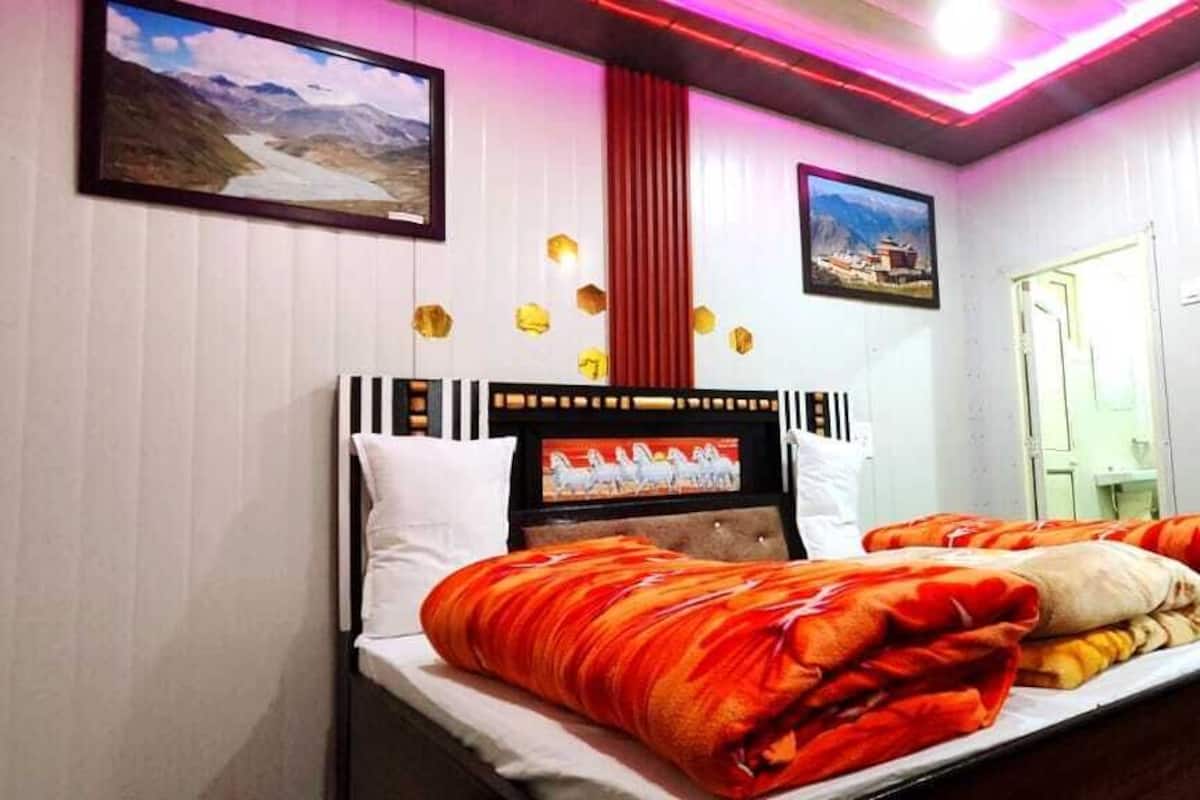 Una habitación de hotel con una cama, televisión y cuadros en las paredes.