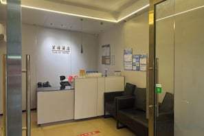 A reception desk with a sign reading 'YUN XI HOTEL' and a waiting area with a couch and a glass partition. - Guangzhou JiaCheng Hotel (Guangzhou)
