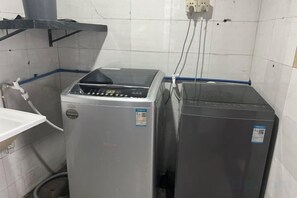 A room with two large appliances, a sink, and a wall-mounted electrical outlet. - Guangzhou JiaCheng Hotel (Guangzhou)