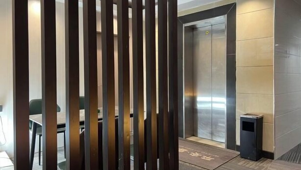 A modern elevator with a metallic finish and a small trash bin beside it. - Guangzhou JiaCheng Hotel (Guangzhou)