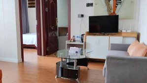 Ett modernt vardagsrum med en grå soffa, ett soffbord i glas och en platt-TV placerad på ett träskåp.