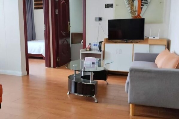 A modern living room with a grey sofa, a glass coffee table, and a flat-screen TV on a wooden cabinet. - Guangzhou JiaCheng Hotel (Guangzhou)