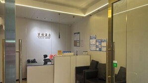 En entré med en receptionsdisk, en svart lädersoffa och en vägg med en skylt där det står "YUN XI HOTEL".