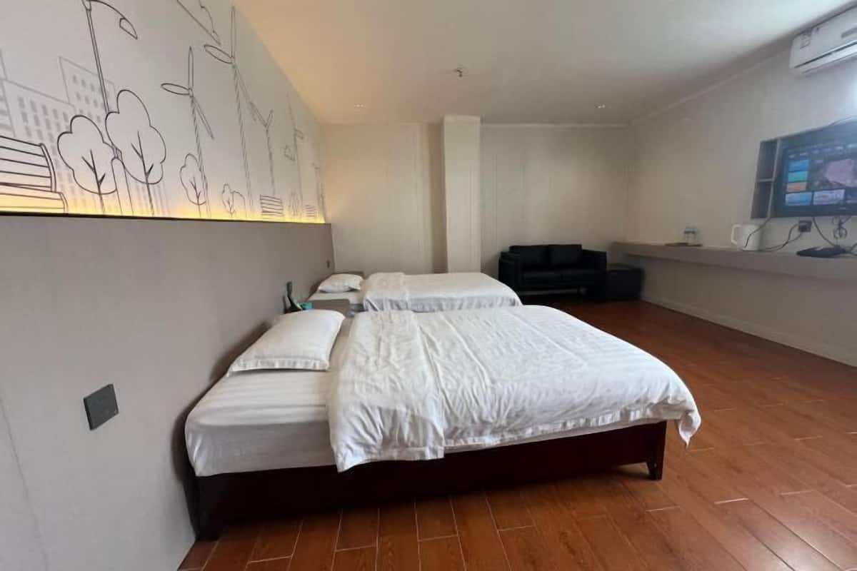 A bedroom with two beds, a TV, and a wall with a cityscape mural.