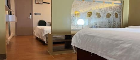 A hotel room with a large bed, a smaller bed, a desk, and a wall with a textured design.