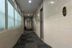A corridor with a tiled floor, a door on the right, and a sign with the number 907 on the wall. - Guangzhou JiaCheng Hotel (Guangzhou)