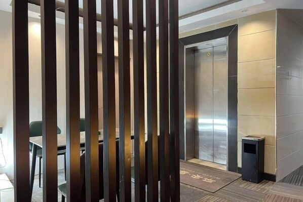 An elevator in a modern building with a metallic finish and a small trash bin beside it. - Guangzhou JiaCheng Hotel (Guangzhou)