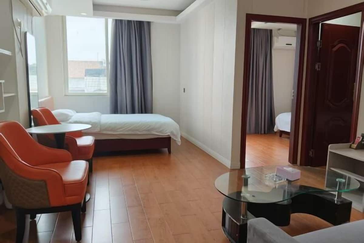 A hotel room with a bed, a small table, two chairs, and a glass coffee table.