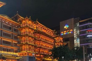 A traditional multi-story building with ornate architectural details, a modern building with a colorful logo, and a clear night sky. - Guangzhou JiaCheng Hotel (Guangzhou)