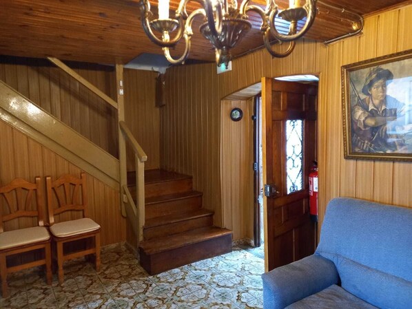 A wooden interior with a staircase, a blue sofa, and a painting on the wall.
