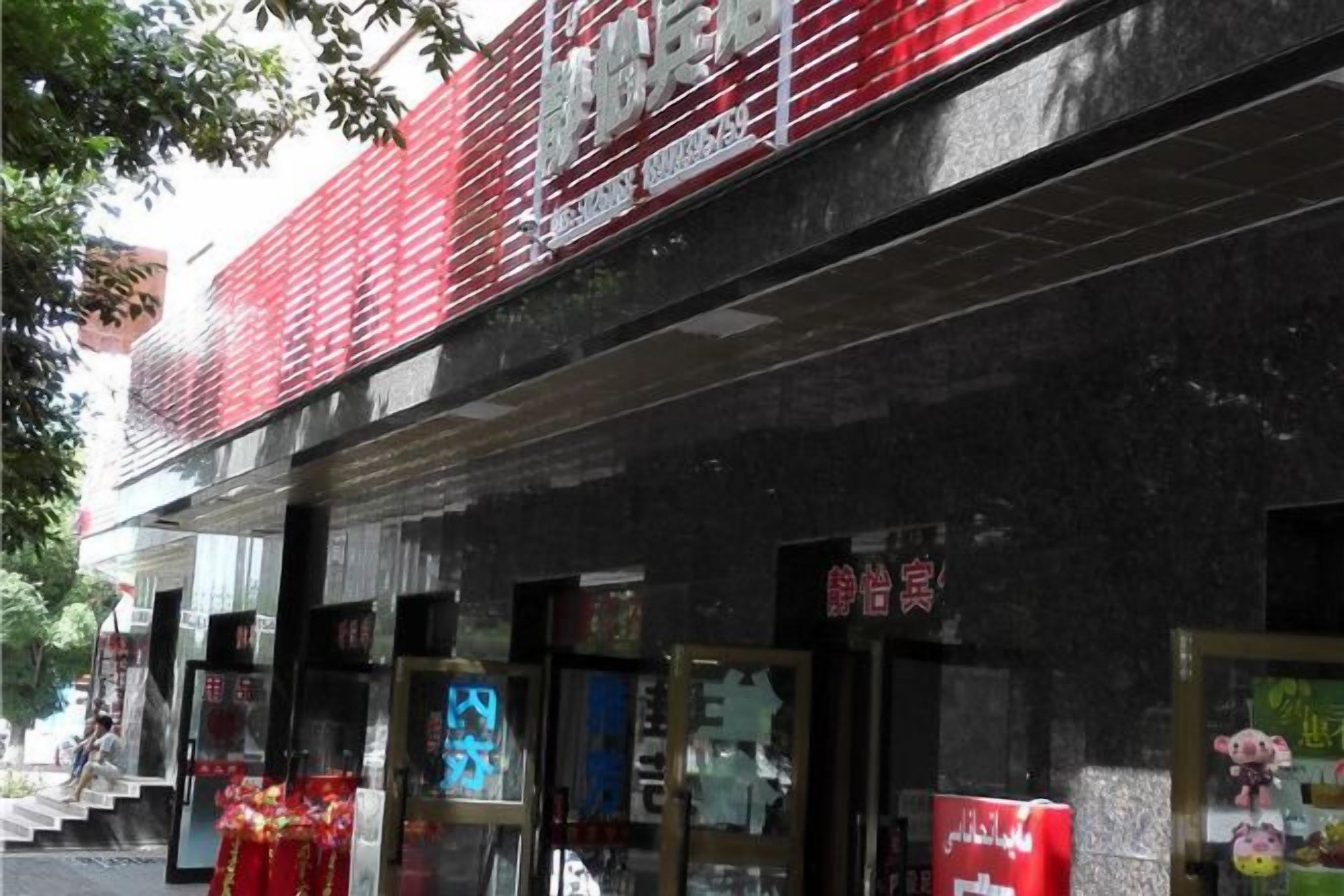A building with a red and black facade, multiple storefronts, and signage in a foreign language.