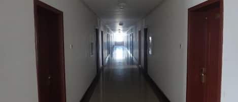 A long, narrow hallway with doors on both sides, leading to a bright end.