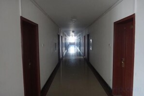 A long, narrow hallway with doors on both sides, leading to a bright end. - Xinyuan Jingyi Hotel (Xinyuan)