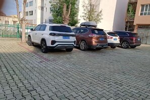 A paved parking area with four SUVs parked in a row. - Xinyuan Jingyi Hotel (Xinyuan)