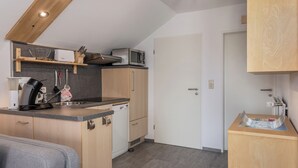 A compact kitchen with wooden cabinets, a microwave, and a dishwasher.