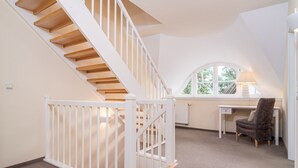 A spacious room with a wooden staircase, a desk, and a chair. - Semi-detached house Villa an der Düne in the Baltic seaside resort of Dierhagen (Ostseebad Dierhagen)