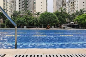 A swimming pool with lane dividers, surrounded by tall residential buildings and greenery. - Real Madrid Holiday Island Style Hotel (Haikou Qilou Old Street) (Haikou)