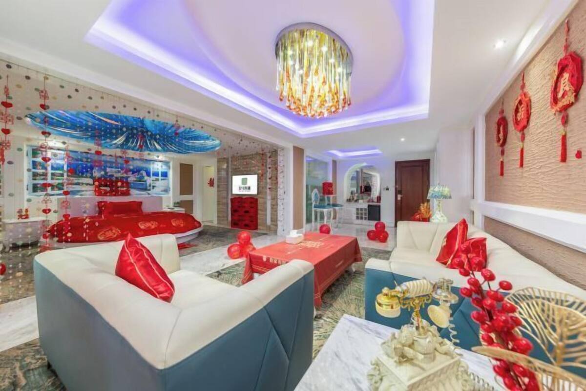 A modern living room with a chandelier, red and white furniture, and decorative elements.