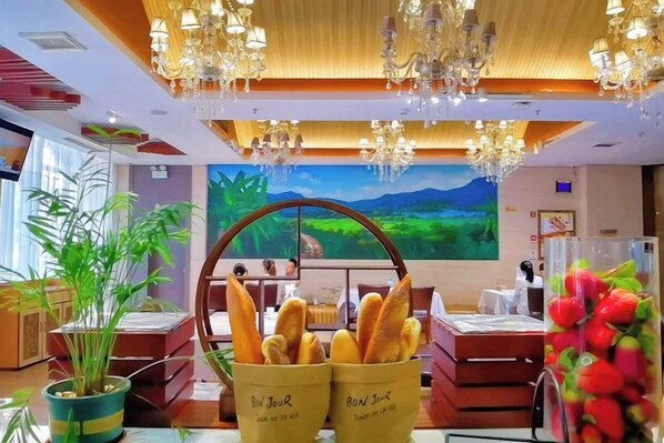 A hotel lobby with a large painting, a chandelier, and a fruit display.