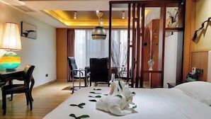 A hotel room with a bed, a desk with a lamp, a chair, and a decorative vase. - Real Madrid Holiday Island Style Hotel (Haikou Qilou Old Street) (Haikou)