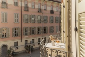 A balcony with a table set for dining, overlooking a row of buildings with uniform architecture. - Linda Apartment 2 in Como (Como)