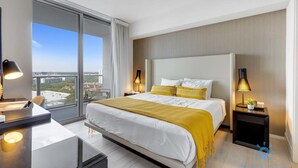 Una camera d'hotel moderna con un letto grande, una scrivania e vista sulla città tramite finestre a tutta parete.