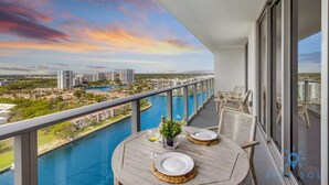 Un balcone con tavolo apparecchiato per due persone, vista su un fiume e sullo skyline cittadino.