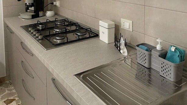 A modern kitchen with white cabinets, a built-in microwave, a gas stove, and a coffee maker. - Garden villa – your relaxed base to explore West Sicily (Custonaci)