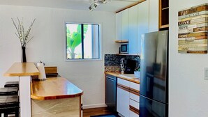 Una cocina moderna con microondas integrado, electrodomésticos de acero inoxidable y un reloj en la pared.