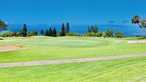 Un campo de golf con vistas despejadas al océano y montañas al fondo.