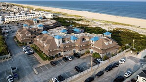Un hotel costero con varias construcciones, estacionamiento y vista a la playa.