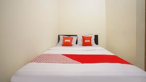 A bed with white bedding and two red pillows with "OYO" text, a red and white patterned throw, and a black headboard. - Hotel O Seturan Near Hartono Mall Yogyakarta Formerly Maleo Kostel (Depok)