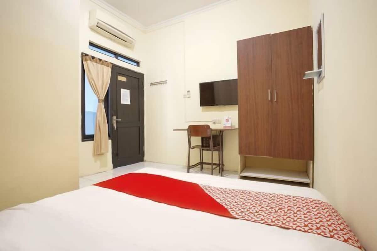 A bedroom with a bed, a desk, a chair, a wardrobe, and a TV.