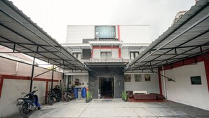 A building with a sign reading "KOST EXCLUSIVE MALEO" and a covered parking area with motorcycles and potted plants. - Hotel O Seturan Near Hartono Mall Yogyakarta Formerly Maleo Kostel (Depok)
